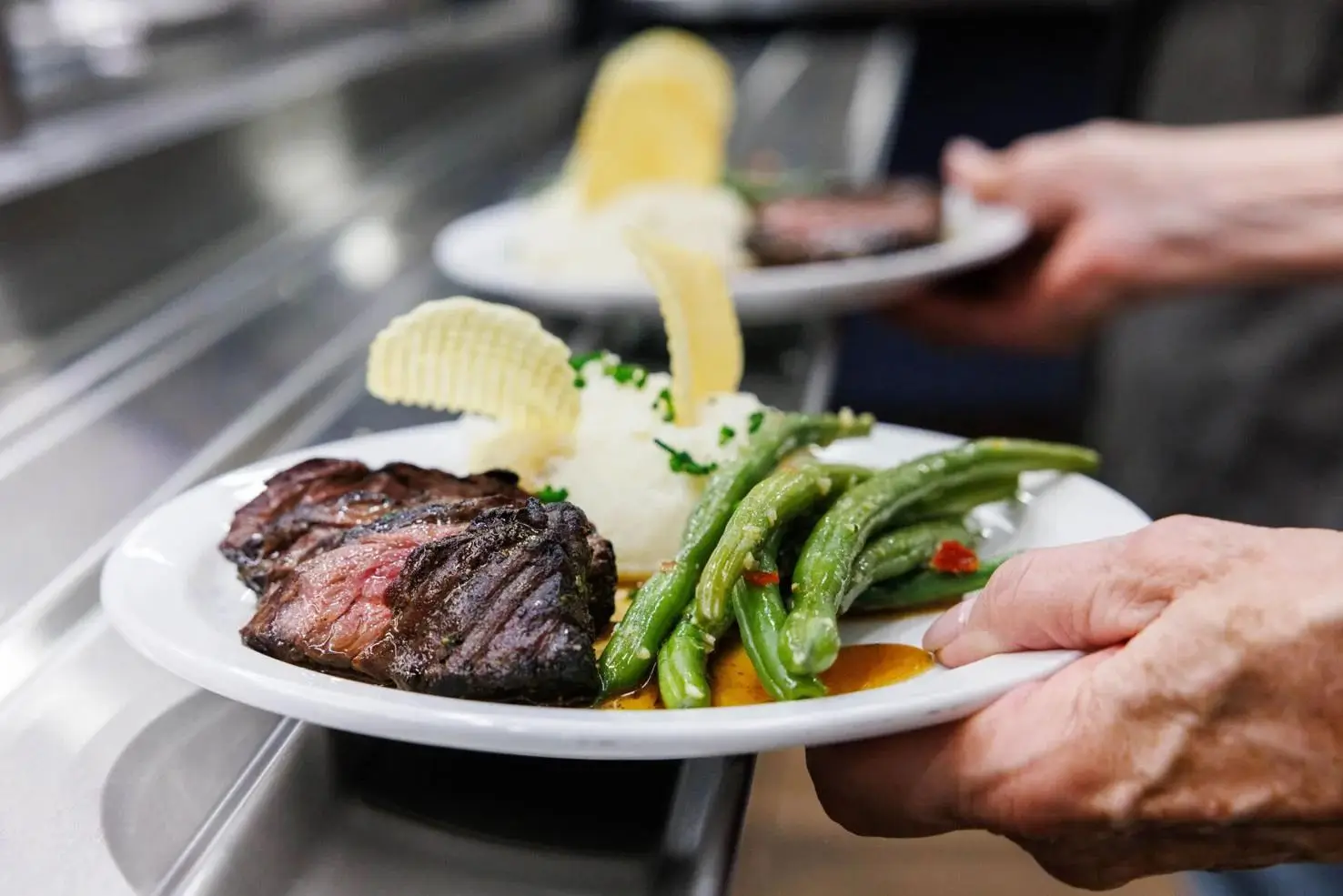 A volunteer carries the entree of hanger steak, mashed potatoes and sautéed green beans during the<br />
20th annual Celebrity Chefs Veterans Day Luncheon for residents of the Yountville Veterans Home on<br />
Wednesday, Nov. 6.<br />
Nick Otto, Register